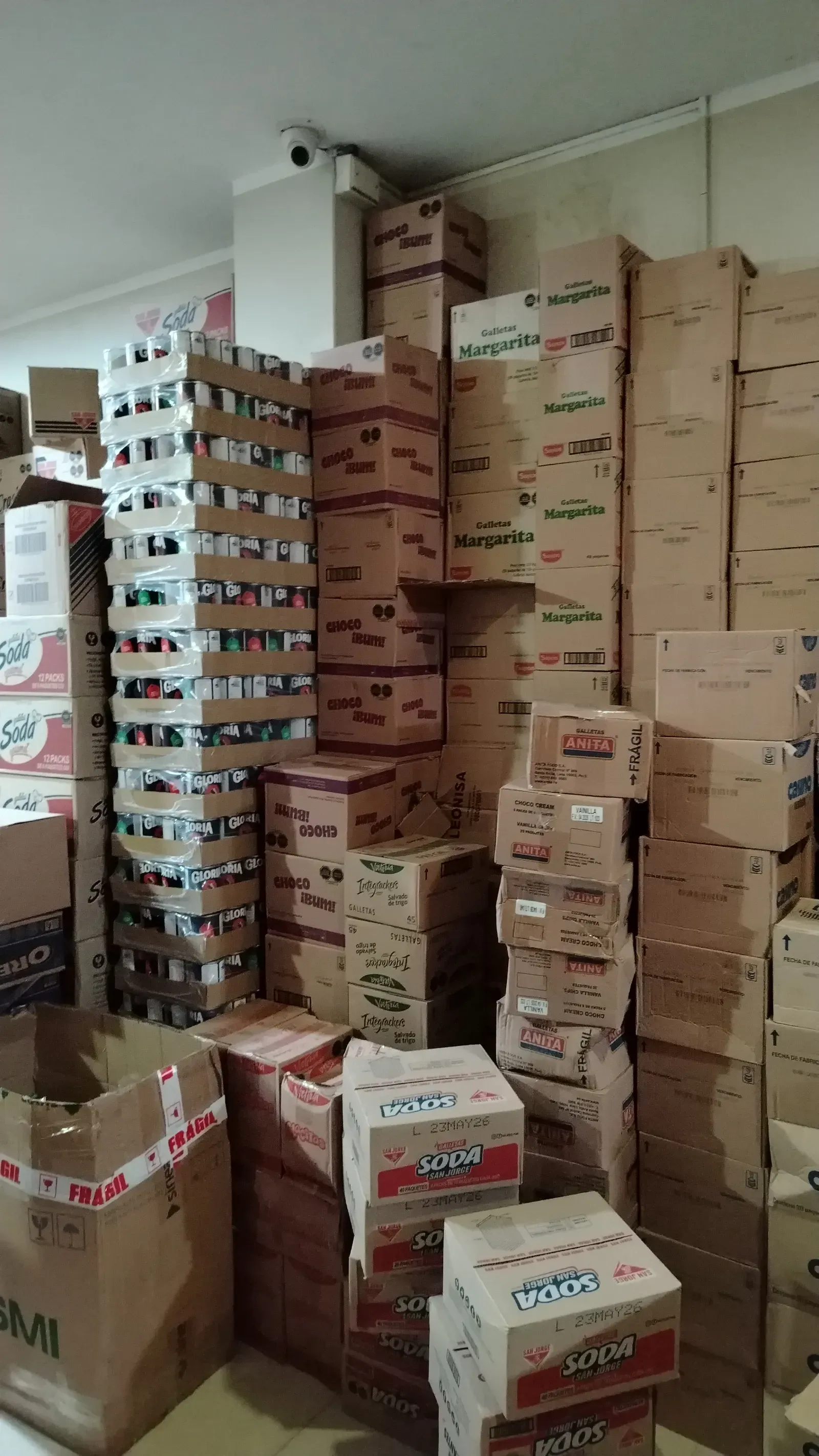 Almacén mayorista con torres de cajas de galletas y gaseosas listas para despacho